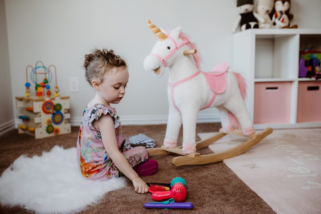 baby girl playing with unicorn rocking horse